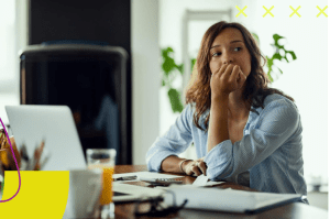 Mulher sentada à mesa de trabalho com olhar distraído simbolizando o presenteísmo