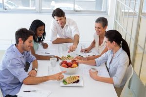 Cinco pessoas sentadas à mesa comem lanches