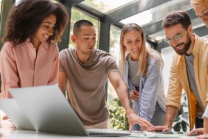 Pessoas em pé conversam sobre papeis na mesa de trabalho