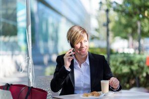 pessoa não-binária sentada em área externa falando ao telefone