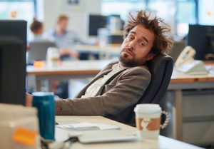 Homem descabelado na mesa procrastina no trabalho