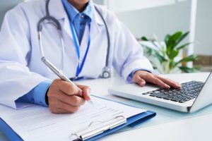 Médico sentado à mesa prescreve exames