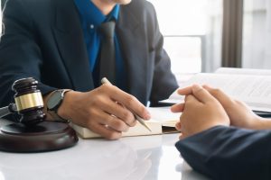 Homens sentados um em frente ao outro e martelo de juiz sobre a mesa