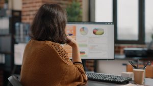 Mulher de negócios analisando gráficos de taxas no computador 