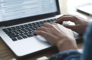 Mãos digitam em teclado de notebook