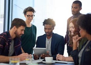 Diversas pessoas reunidas em war room para portal do colaborador em volta de mesa 