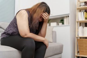 Mulher esgotada no sofá de sua casa sem work-life balance