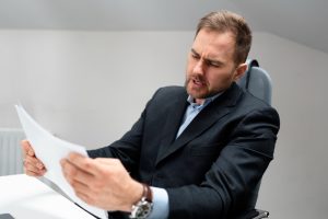 Homem revisa repetidas vezes o mesmo trabalho e não foca no essencial, uma atitude típica de quem pratica a autossabotagem