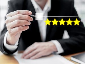 Homem de terno sentado usa sua caneta para avaliar a empresa com cinco estrelas, mostrando a boa reputação de quem adota SSMA
