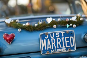 Fotografia de placa de automóvel com texto JUST MARRIED e enfeites de coração simbolizando a licença casamento