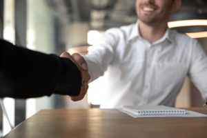  Dois homens se cumprimentam pelo novo emprego e não usam papeis porque fizeram o processo de admissão digital