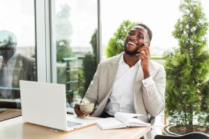  Homem sorri enquanto fala ao telefone e mostra características de um empreendedor