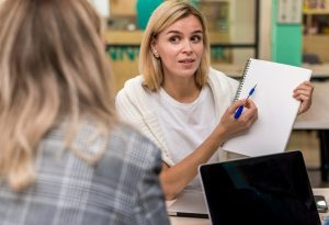 Profissional feminina em segundo plano desfocado com um tablet e uma caneta em primeiro plano, em ambiente corporativo, mostrando o que é Employee Value Proposition