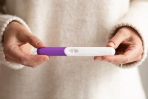 Mulher segura teste de gravidez, um dos exames que não podem ser pedidos no ASO
