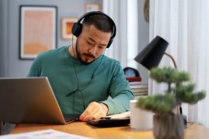 homem trabalha em home office com fone de ouvido simboliza o job description de quem trabalha em casa