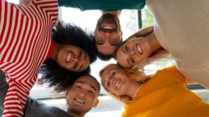 Diversos colaboradores unidos sorriem para a câmera mostrando a diversidade resultante do processo de recrutamento misto 