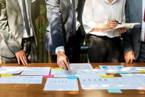 Profissionais analisam e conversam sobre um o processo de inbound recruiting enquanto olham papéis e post-its sobre uma mesa