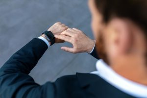 Homem olha no relógio para chegar pontualmente ao ASO admissional