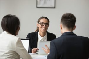 Profissional de recrutamento sorridente conversa com dois candidatos durante inbound recruiting