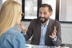 Homem conta sua trajetória para recrutadora respondendo às perguntas para entrevista de emprego
