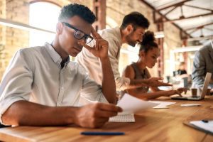 Colaboradores sentados à mesa fazem o teste big five
