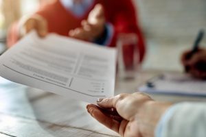 Pessoa entrega currículo impresso para recrutador, simbolizando o modelo operacional de recrutamento, que se opõe ao recrutamento inteligente