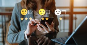 Colaboradora responde à pesquisa de satisfação pelo celular em frente ao notebook
