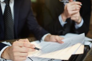 Dorso masculino em close segurando um contrato de trabalho com cláusulas estabelecidas pela convenção coletiva de trabalho