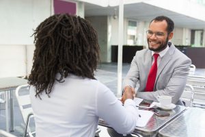 Homem e mulher conversam em café durante entrevista de emprego, situação propícia para demonstrar soft skills