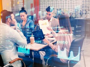 Pessoas em reunião e gráficos tecnológicos simbolizam reunião de trabalho com ferramentas tecnológicas