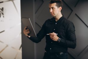 Profissional com execução de alta performance em pé analisando dados em um tablet em um ambiente de escritório moderno
