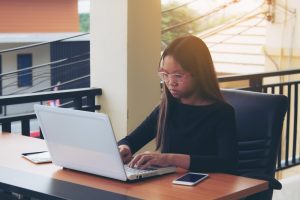 Mulher trabalhando em sacada acessa sua convenção coletiva de trabalho no computador
