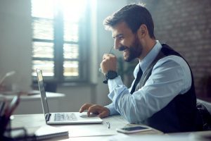 Homem trabalha com ar vitorioso simbolizando um profissional que realiza um trabalho de excelência