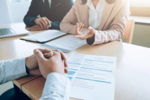 Pessoas conversam em entrevista de emprego usando currículo e carta proposta