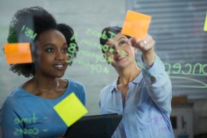  duas mulheres trabalham juntas praticando soft skills como trabalho em equipe, organização e planejamento