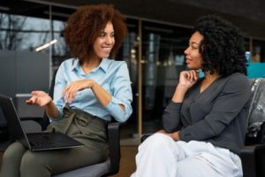 Duas mulheres conversando sobre como deve ser implementada a transparência salarial