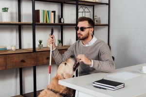 homem com cão guia trabalha na empesa não capacitista