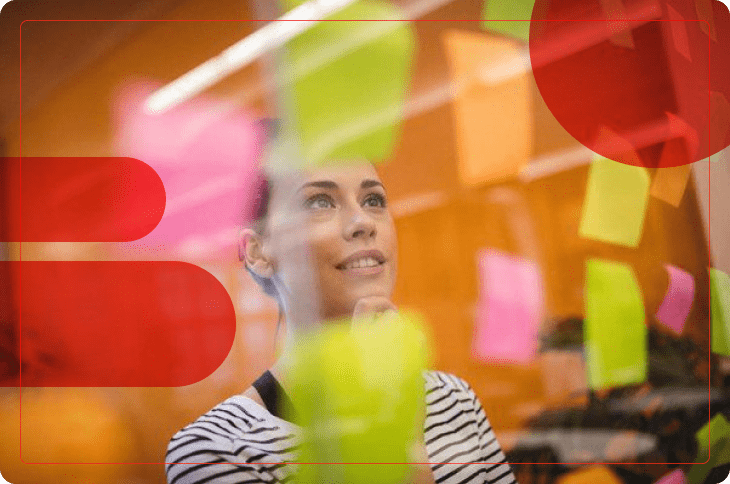 Mulher observa post-its em mural e exerce a adaptabilidade