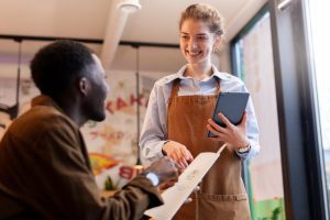mulher no trabalho sazonal vendendo para um cliente que está olhando o cardápio