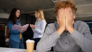 Jovem funcionário exausto em ambiente de trabalho com liderança tóxica