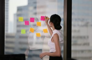  mulher que trabalha no modelo sazonal anotando em papeis colados no vidro suas dificuldades