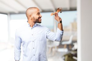 Homem sorridente de perfil segura um avião 