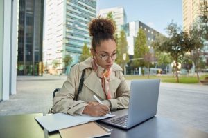 mulher segurando uma caneta, utilizando um computador para estudar como melhorar a sua adaptabilidade no ambiente corporativo
