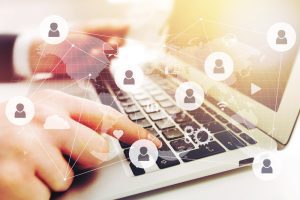 homem digita em teclado de note com ilustrações de pessoas simbolizando a integração das informações pela GFIP