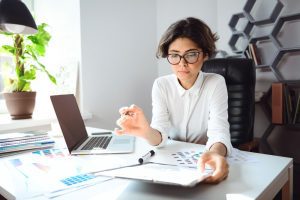Mulher no trabalho analisa papeis e faz retificação da GFIP