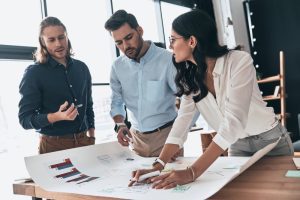colaboradores da escala 12x36 analisando dados em uma cartolina em cima de uma mesa 