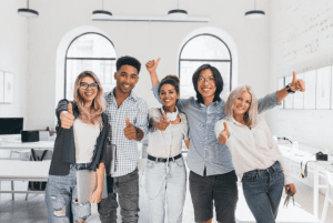Cinco pessoas sorrindo para a câmera exemplificam a satisfação da empresa gerenciar bem atestados como o Cid acompanhante