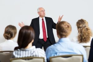 homem com os braços abertos dando um workshop para os seus colaboradores