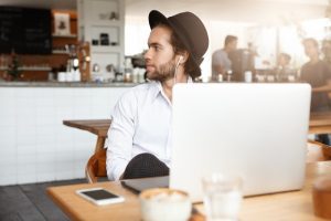 Profissional com contrato freelancer trabalha de seu computador numa cafeteria