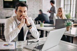 Profissional sentado à mesa do trabalho demonstra resignação 